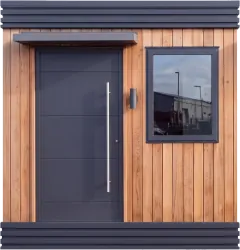 The front of a meanwhile home: timber cladding, a dark front door under a small canopy, and a window.